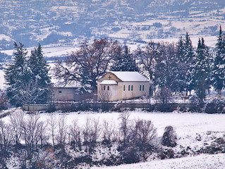 Small orthodox christian church in a cemetery on snow covered land, in Pieria, Macedonia, Greece.