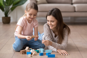 Smiling mom and little daughter playing with toy blocks