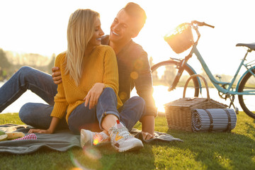 Happy young couple having picnic near lake on sunny day - Powered by Adobe