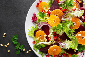 Christmas salad with boiled beet, red onion, tangerines, pomegranate, parsley, pine nuts and lettuce leaves