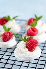 Mini Pavlova meringue with whipped cream and raspberries.