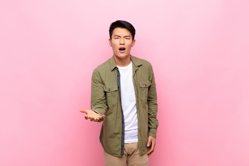 young chinese man looking angry, annoyed and frustrated screaming wtf or what‚Äôs wrong with...