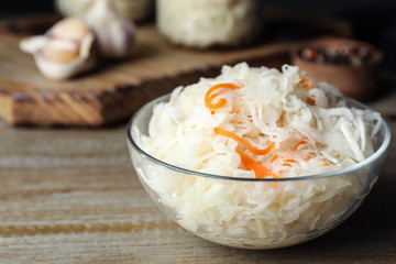 Tasty fermented cabbage on wooden table, closeup