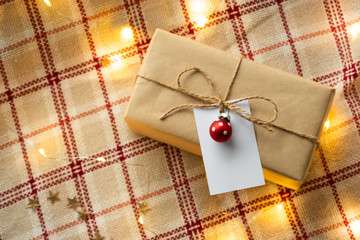 Craft paper wrapped gift with brown craft paper card tag on plaid. Christmas handmade present for Merry Christmas and New year holiday. 