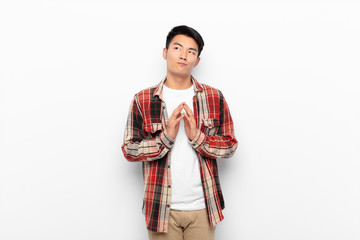 young chinese man scheming and conspiring, thinking devious tricks and cheats, cunning and...
