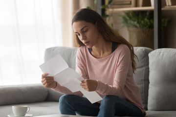 Focused young woman read correspondence letter at home