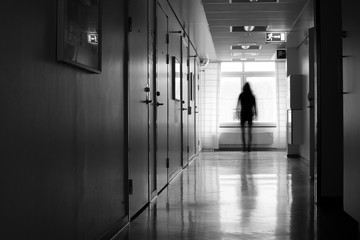 Silhouette of person in motion blur in front of window in a hostpital corridor.