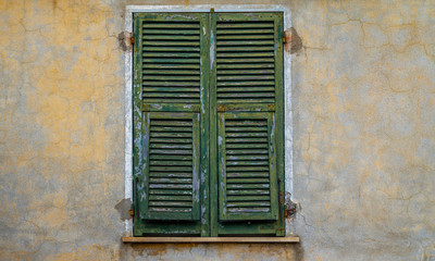 Obraz premium Old building in italian village. Stone wall with windows and shutters. Building with beautiful old architecture. Old window on old wall. Architecture and landmark.