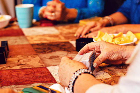 Close up of senior women's hands playing cards at table