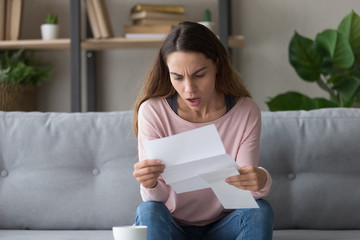 Shocked young woman stunned by bad news in letter