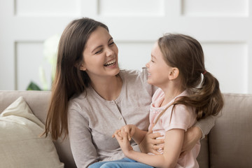 Smiling young mom and daughter have fun laughing