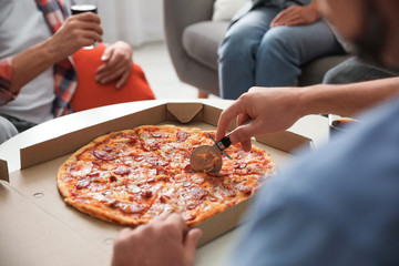 Man cutting fresh pizza on table, closeup