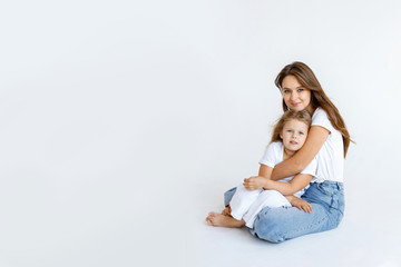 Obraz na płótnie Canvas Happy mom and daughter cuddling on a white background. Happy family concept