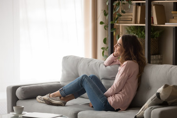 Obraz premium Smiling young woman relax on sofa dreaming