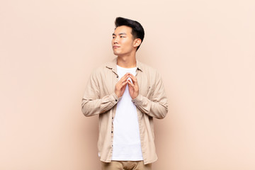 young chinese man feeling proud, mischievous and arrogant while scheming an evil plan or thinking...