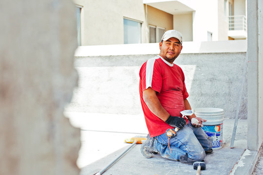 Bricklayer with tools kneeling on worksite