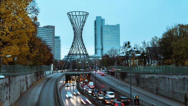 Munich traffic timelapse with illuminated street traffic with bavarian skyscraper in the background. Teal sunset color in city skyline.