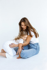 Obraz premium Happy mom and daughter are hugging and spending time together on a white wall background. Happy family concept
