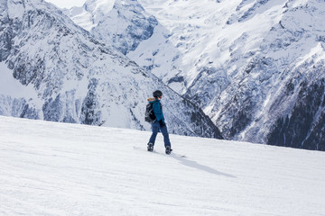 Woman snowboarder rides downhill on a slope.