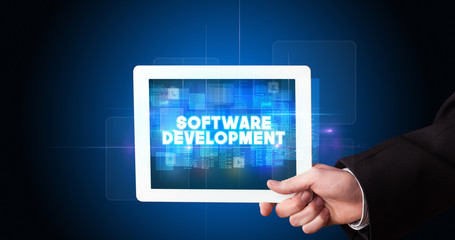 Young business person working on tablet and shows the inscription: SOFTWARE DEVELOPMENT