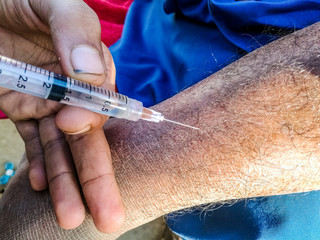 a nurse is injecting in the nerve of a sick man in the hospital 