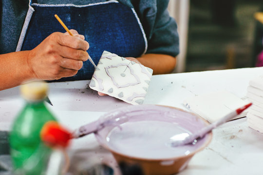 Close up of woman decorating tiles in factory