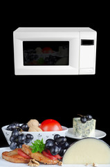 Heating and cooking in the microwave. Meat and ingredients on white dish and black background. Microwave in the background