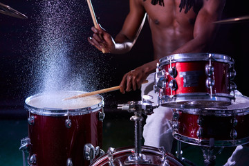 african man playing on drums in rain, water, drops on drums. percussion instruments