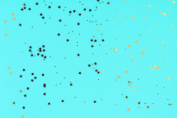 Golden stars glitter confetti on blue background. Festive backdrop.