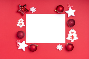 New Year and Christmas frame composition. Blank sheet of paper with christmas decorations on red background. Top view, flat lay, copy space