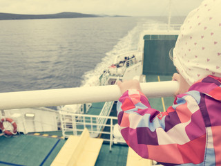 Rear view of a cute girl enjoying a ferry ride in cloudy weather.