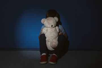 Little boy with teddy bear near blue wall. Domestic violence concept