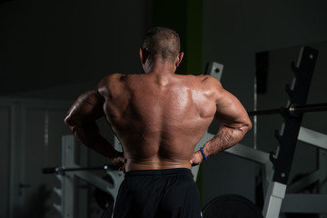Fototapeta na wymiar Muscular Mature Man Flexing Muscles In Gym
