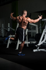 Obraz na płótnie Canvas Mature Muscular Man Flexing Muscles In Gym