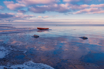Stunning winter sunset on the frozen Peipsi lake near the fishers Nina village in Estonia, the old boat in the water