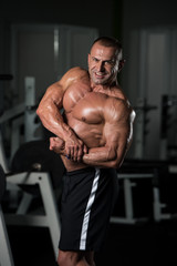 Fototapeta na wymiar Mature Bodybuilder Posing Biceps After Exercises