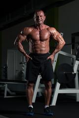 Obraz na płótnie Canvas Muscular Mature Man Flexing Muscles In Gym