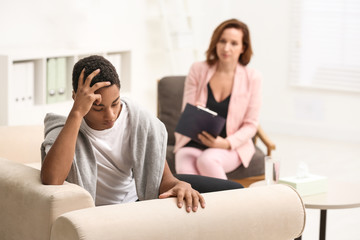 Psychotherapist working with teenage African-American boy in office