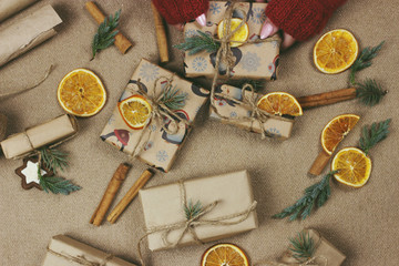 Fototapeta premium A woman wraps Christmas presents in wrapping paper and ties a ribbon bow. Close-up of woman's hands preparing surprises for the new year. Workflow of a derator. Desktop.