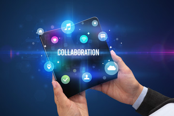 Businessman holding a foldable smartphone with COLLABORATION inscription, social media concept