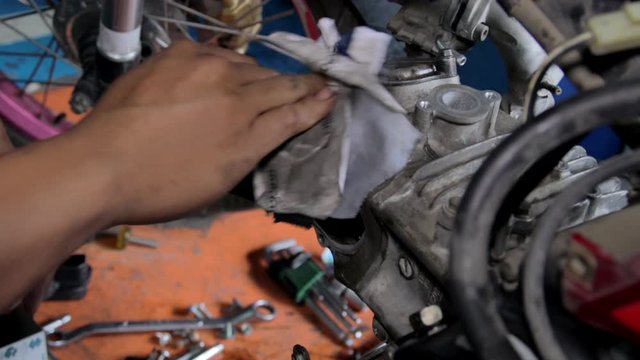 Mechanic Wiping Down And Cleaning Plate And Engine Area On Motorbike