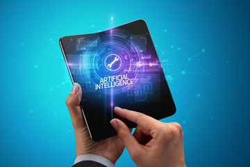 Businessman holding a foldable smartphone with MACHINE inscription, new technology concept ARTIFICIAL INTELLIGENCE