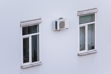 Two windows and air conditioning on a white wall.