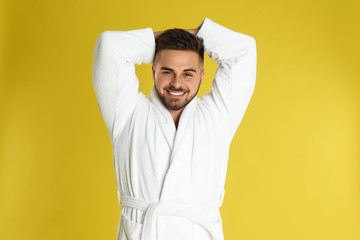 Happy young man in bathrobe on yellow background - obrazy, fototapety, plakaty