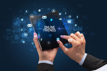 Businessman holding a foldable smartphone with ONLINE FRIENDS inscription, social networking concept