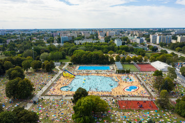 Top view of the city pool in Warsaw, Crowds of people sunbathe and swim in the blue water under the open sky. Poland.