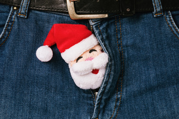 Santa Claus peeks out of open zipper on jeans. Concept on the topic of intimate relationships. Bad Santa - obrazy, fototapety, plakaty