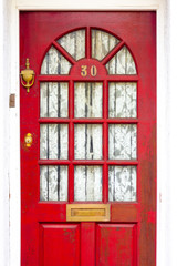 House number 30 on a red wooden door with glass panels