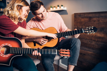 boyfriend and girlfriend spend time together playing the guitar at home, isolated, indoors