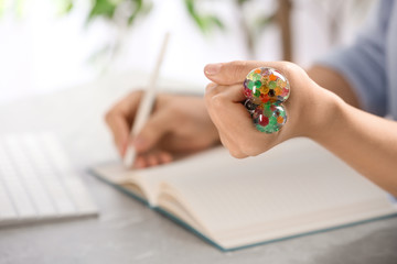 Woman squeezing colorful slime in office, closeup. Antistress toy